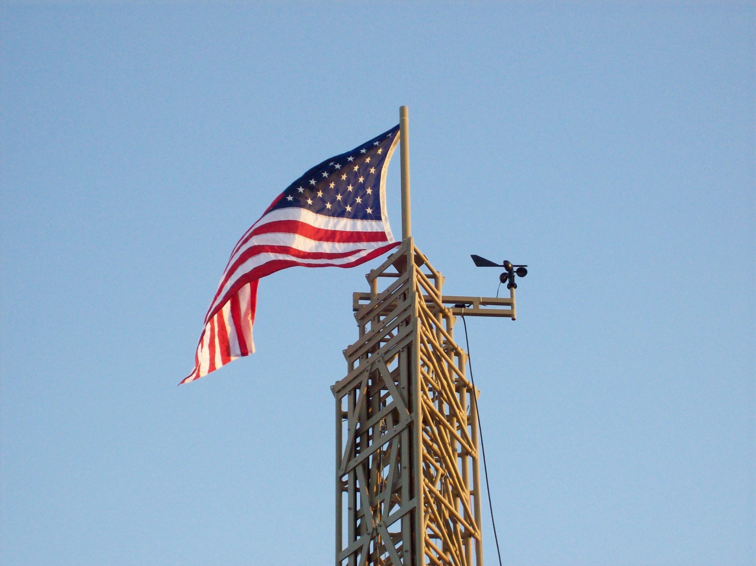 Aluma Self-Monitoring Automatically Retracting Tower in sky with American flag at the top